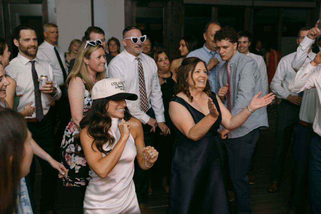 Bride dancing with guests in custom ball caps during the reception