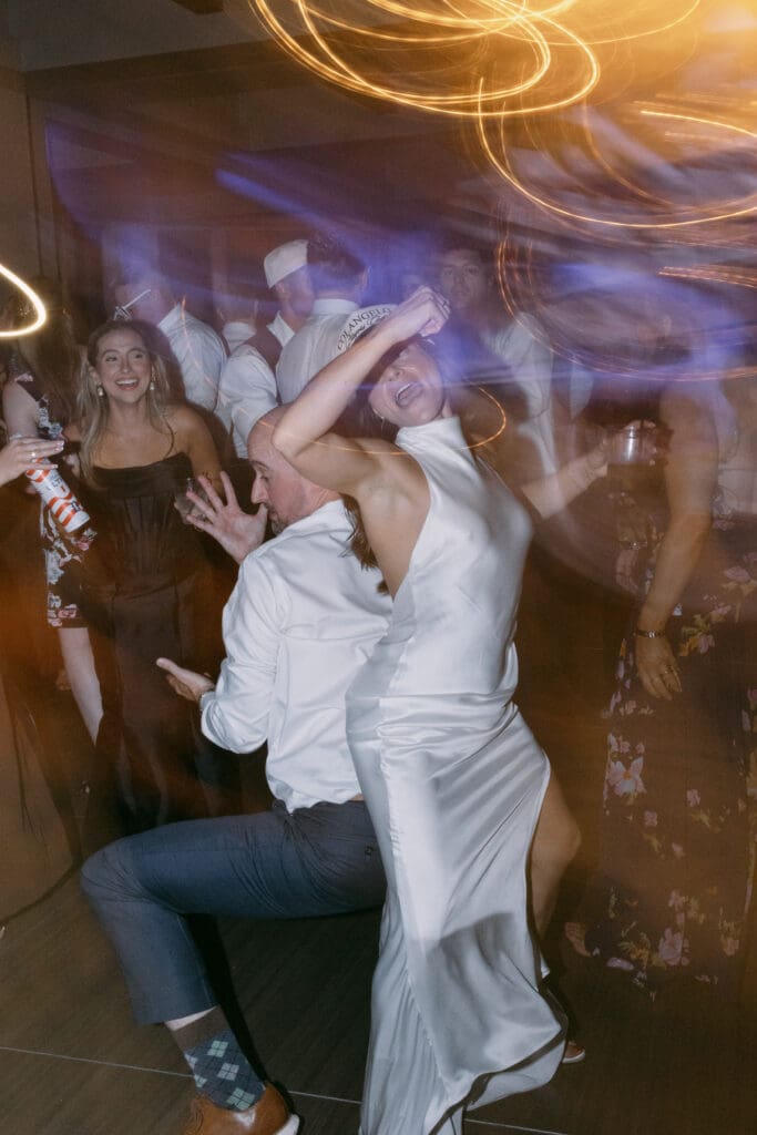 Bride and guests dancing under swirling party lights