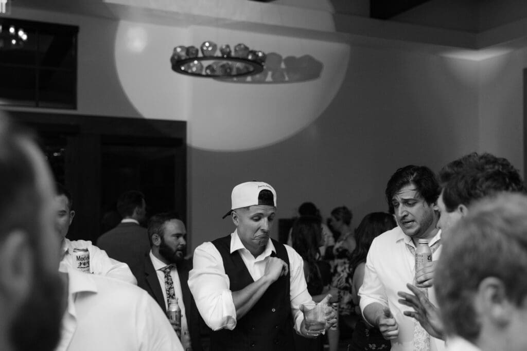 Groomsmen in ball caps dancing and cheering in black and white