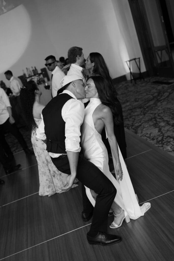 Groom dips his bride for a kiss on the dance floor in black and white