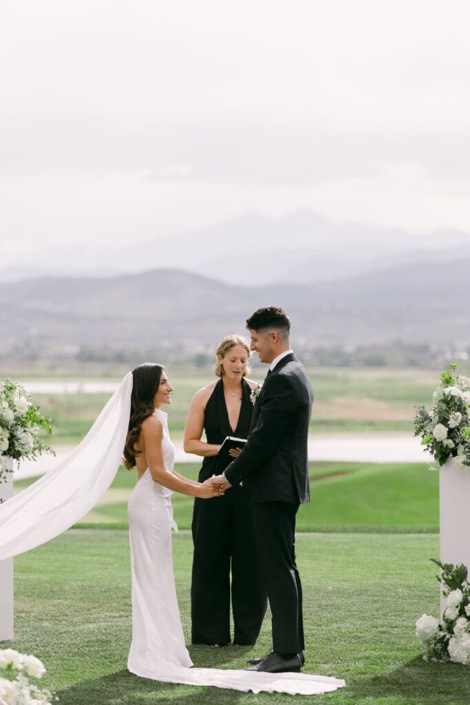 Bride and groom holding hands as the officiant leads their vows