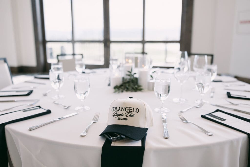Custom ball cap waiting at a place setting on a white reception table