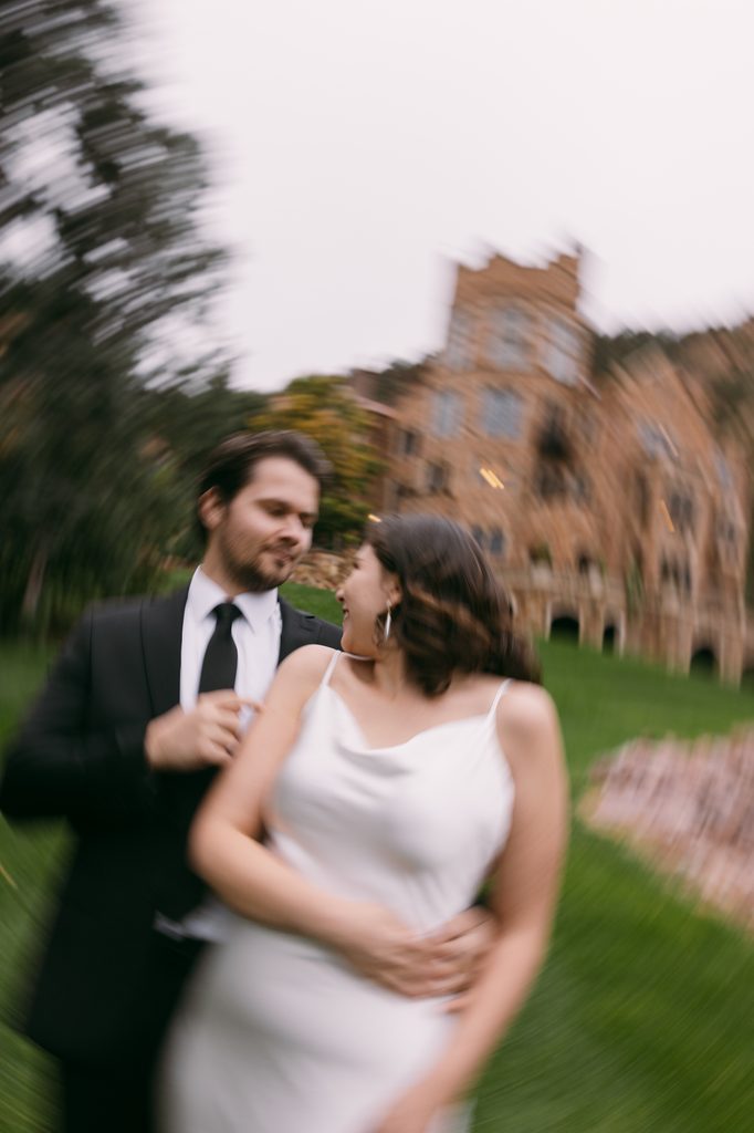 Motion-blurred portrait of Logan holding Bridgette from behind on the castle grounds