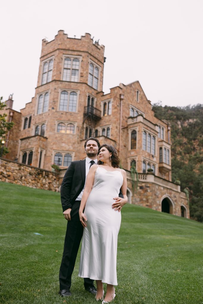 Engaged couple standing together beneath the tower of Glen Eyrie Castle