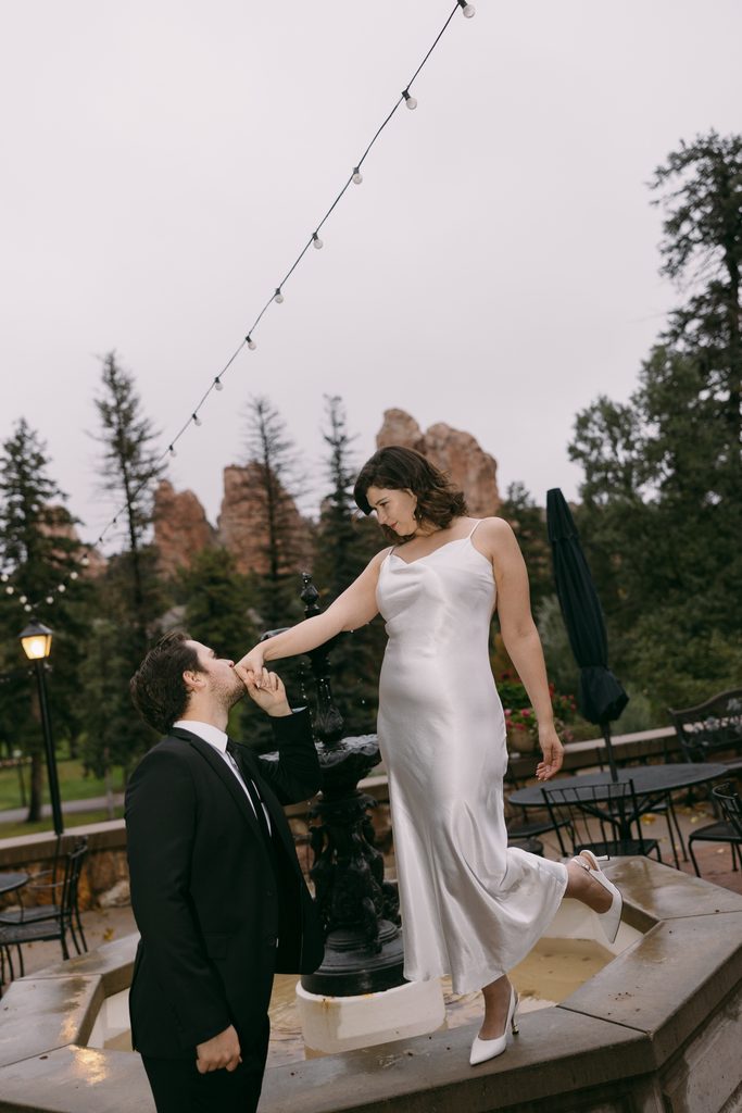 Logan kisses Bridgette's hand as she stands on the edge of the fountain