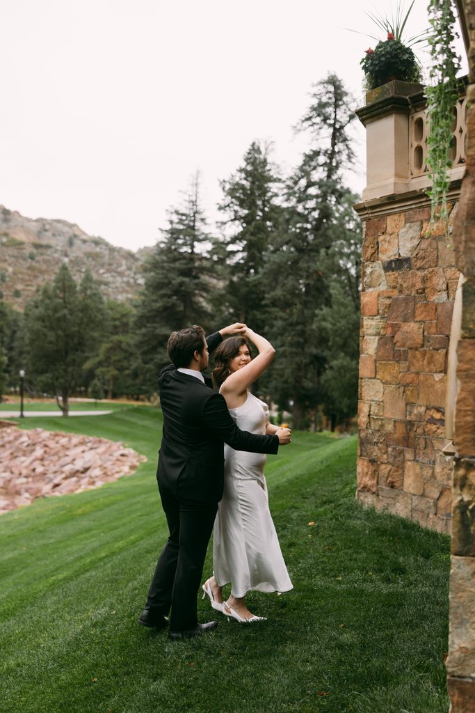 Logan twirls Bridgette on the green lawn beside the castle walls